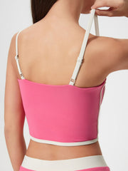 Fuchsia pink contour-trimmed crop top with white piping and adjustable straps.