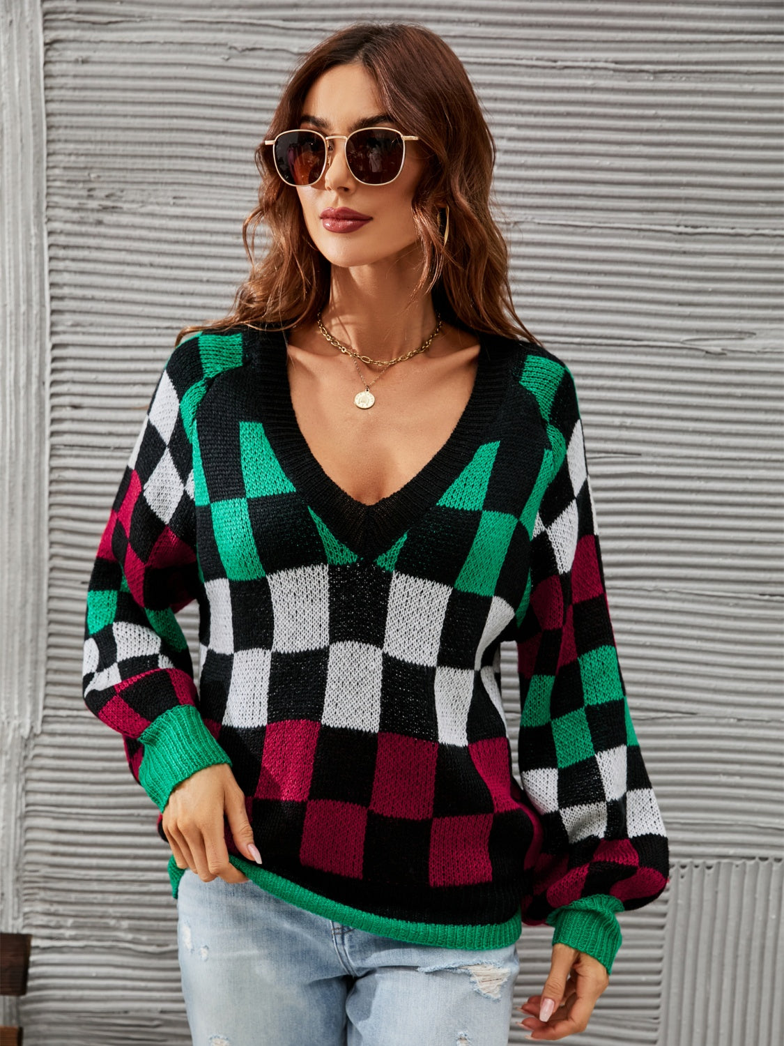 Geometric knit sweater with puff sleeves and V-neck in black, green, white, and burgundy checkerboard pattern.