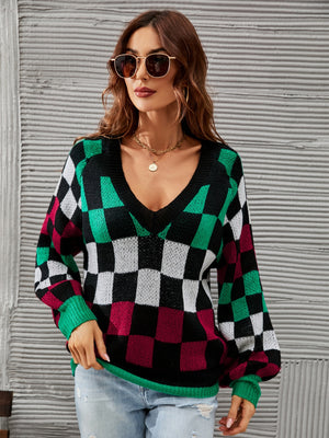 Geometric knit sweater with puff sleeves and V-neck in black, green, white, and burgundy checkerboard pattern.