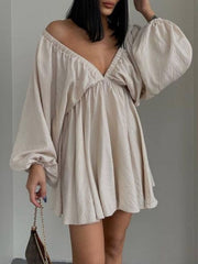 Beige ruched V-neck dress with balloon sleeves and a flowy skirt.