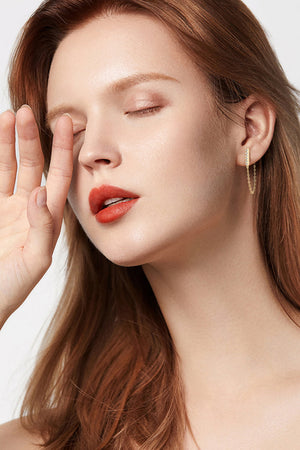 Gold chain cascade bar earrings with a delicate chain drop, worn by a woman.