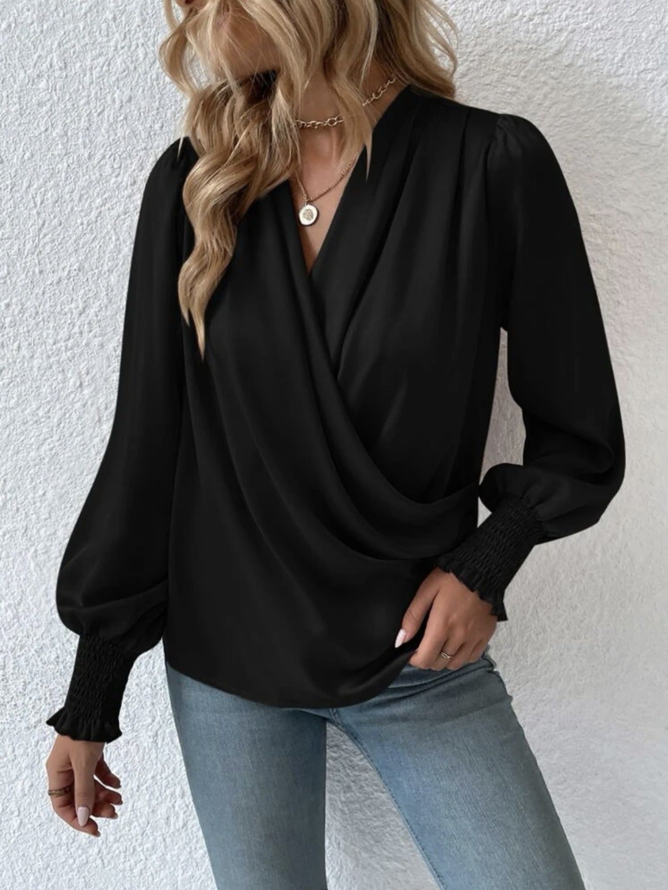 Black ruched surplice blouse with long balloon sleeves and smocked cuffs.