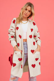 Cream longline knit cardigan with red heart motif, pockets, and ribbed trim.