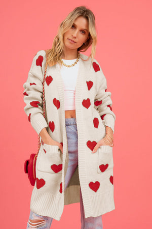 Cream longline knit cardigan with red heart motif, pockets, and ribbed trim.