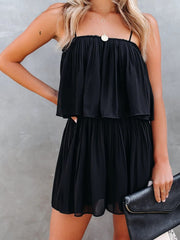 Black tiered cami romper with delicate straps and pleated skirt detail.