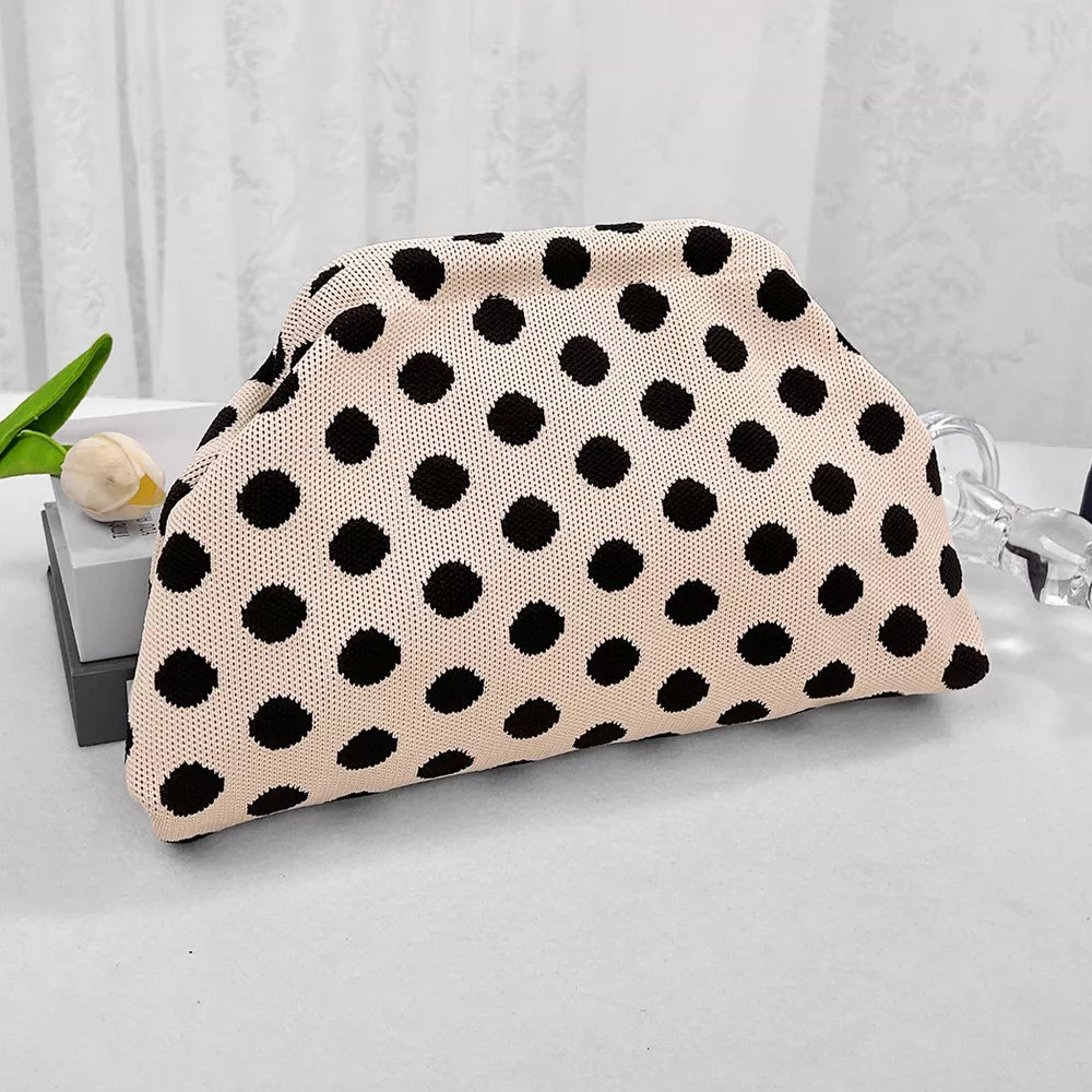 Knit clutch bag with black polka dots on a light pink background.