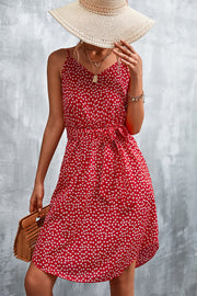Red daisy print slip dress with tie waist, V-neck, and spaghetti straps.