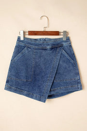 Denim wrap skort in medium wash with asymmetrical hem and patch pockets.