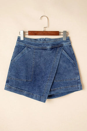 Denim wrap skort in medium wash with asymmetrical hem and patch pockets.