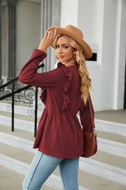 Textured ruffle peplum blouse in wine with long sleeves and a cinched waist.