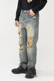 Distressed baggy denim jeans in medium wash with shredded knees and a casual fit.