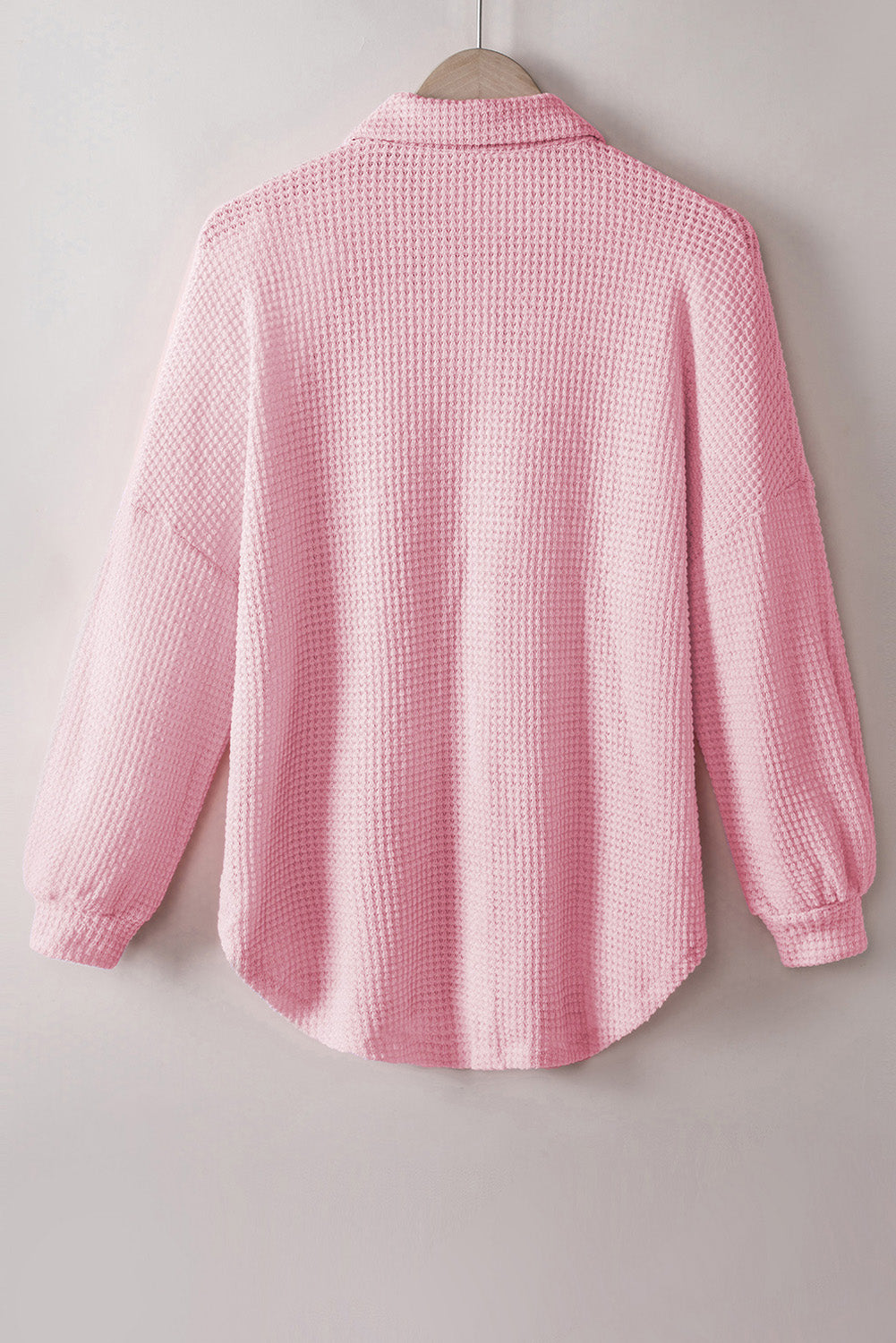 Blush pink waffle knit button-down shirt jacket with long sleeves and a curved hem.