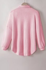 Blush pink waffle knit button-down shirt jacket with long sleeves and a curved hem.