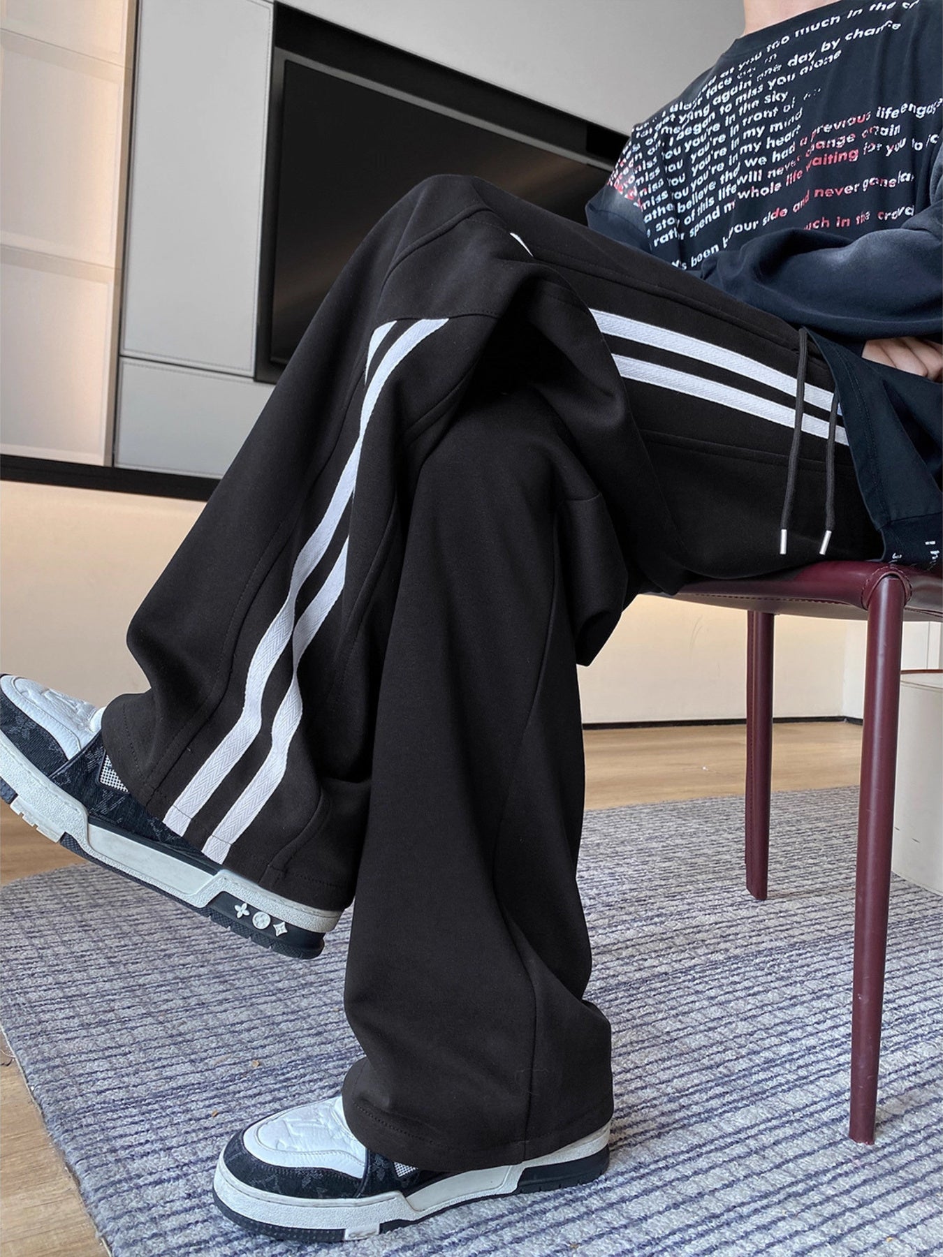 Men's black wide-leg sweatpants with white side stripes and drawstring waist.