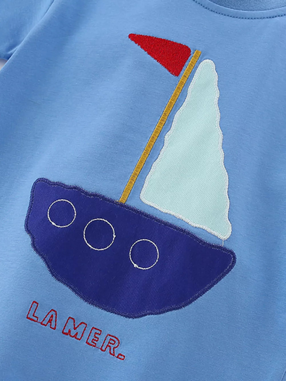 Light blue cotton t-shirt with embroidered sailboat graphic and "LA MER" text.