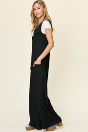 Black wide-leg pocket jumpsuit with deep V-neck, shown layered over a white t-shirt.
