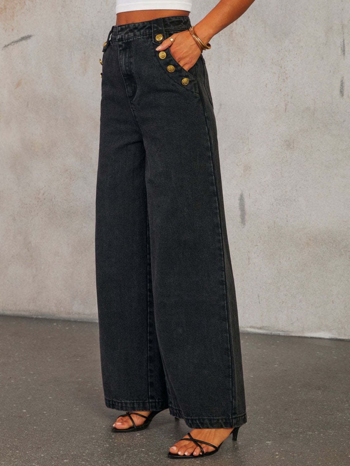 Dark wash denim wide-leg jeans with gold button detail and a high waist.