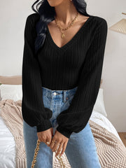 Black blouson top with textured chevron pattern, V-neck, and balloon sleeves.