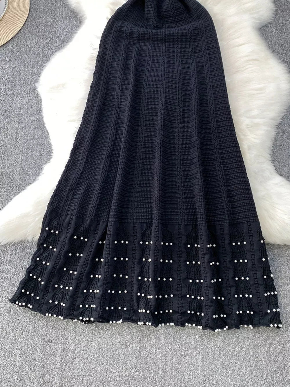 Black knit midi dress with textured pattern and pearl details at hem.