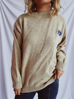Relaxed knit sweater in dark gray or tan, acrylic, with embroidered character detail.