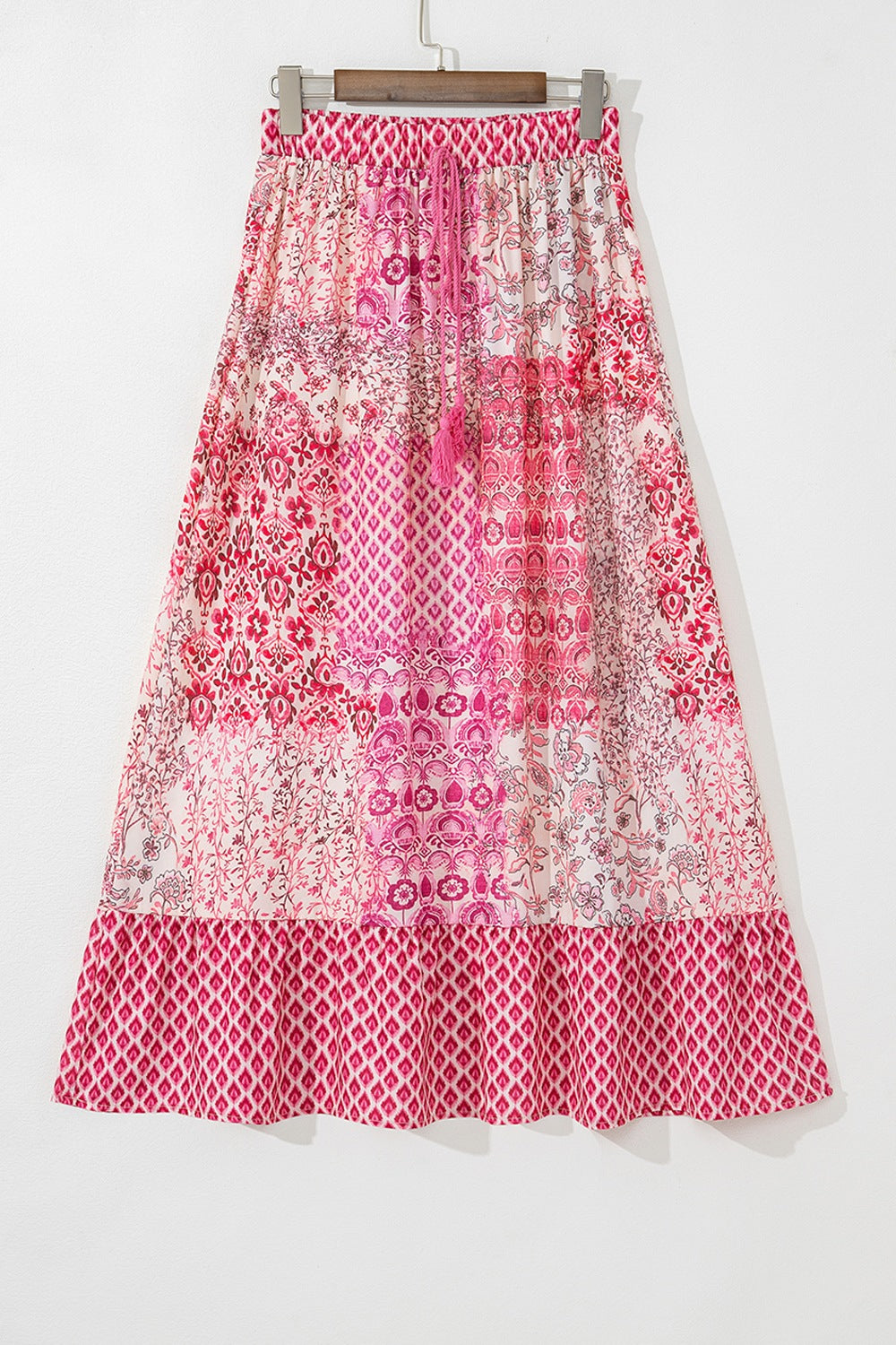 Printed tiered maxi skirt in dusty pink with tassel detail and boho pattern.