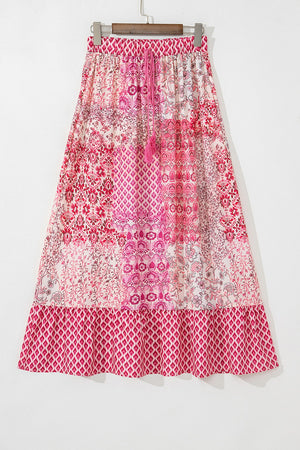 Printed tiered maxi skirt in dusty pink with tassel detail and boho pattern.