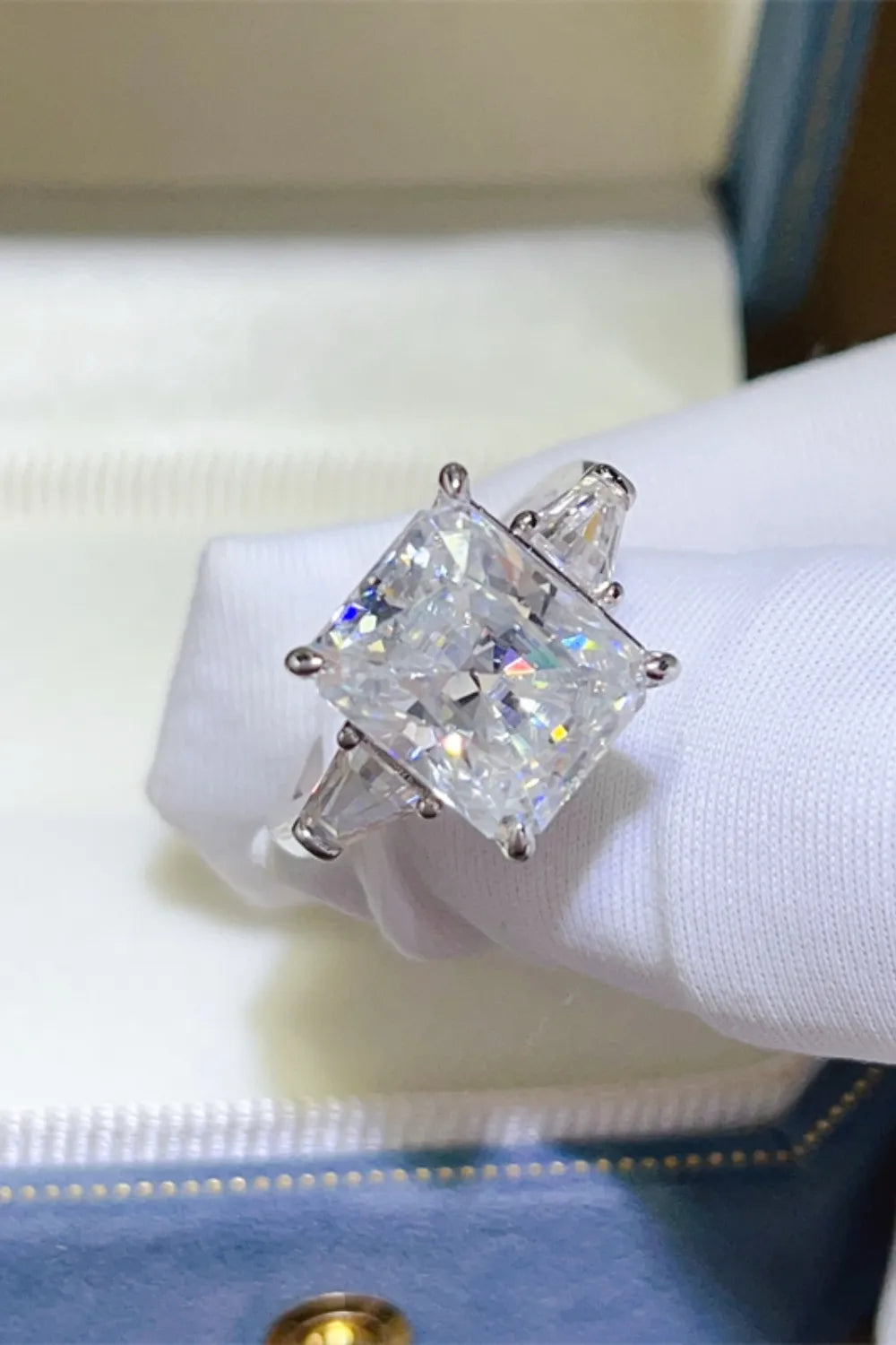 Silver ring with radiant cut moissanite center stone and trapezoid side stones.