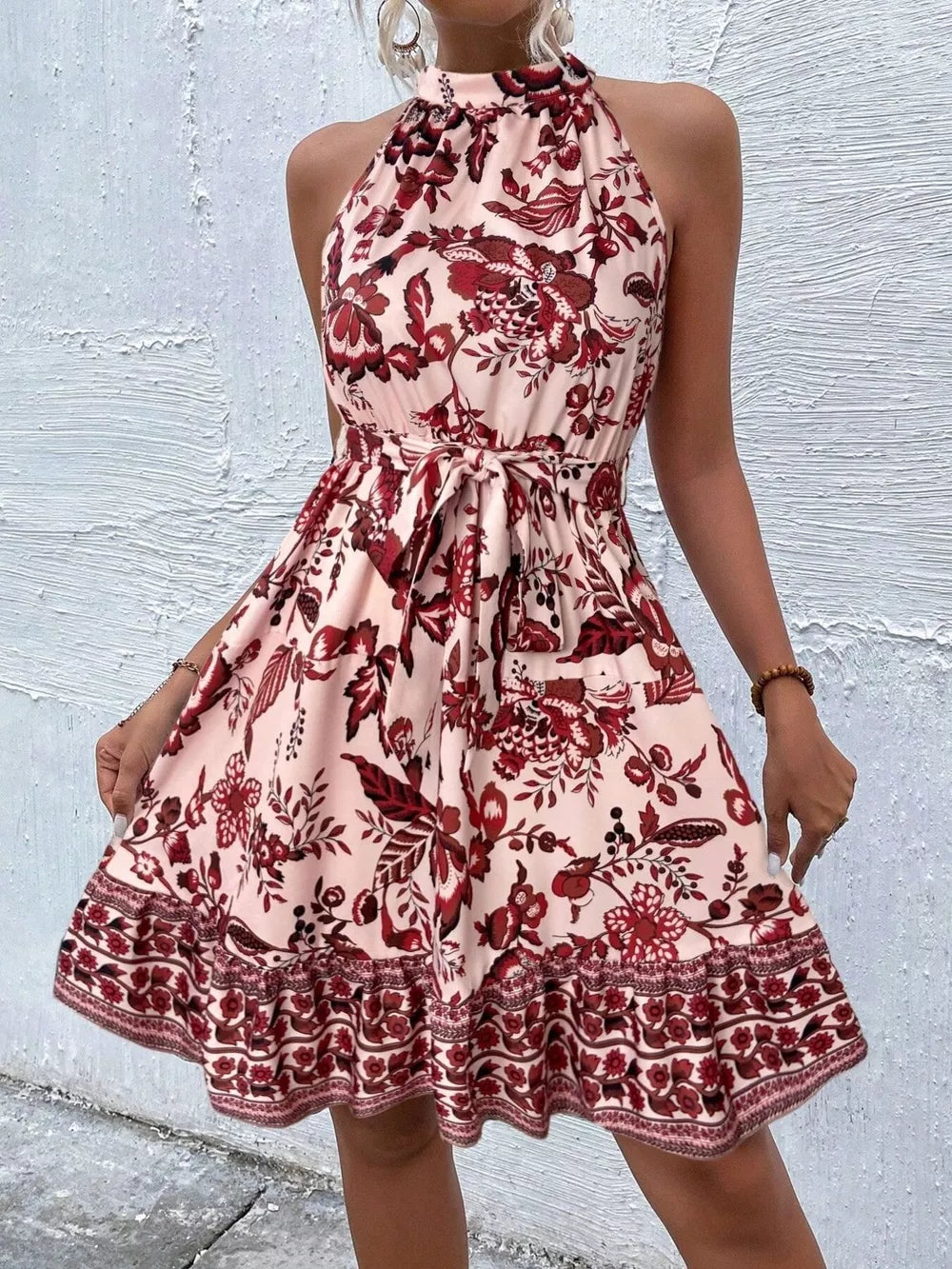 Floral print halter neck tie-waist mini dress with ruffled hem in burnt coral.