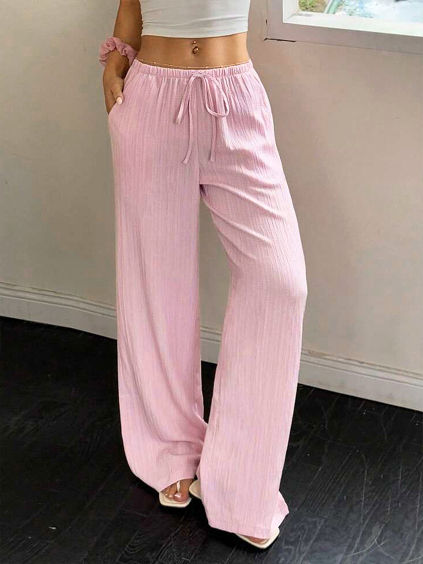 Pink crinkled wide leg pants with drawstring waist and pockets.