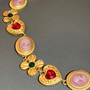 Gold statement necklace with cameo, flower, and heart charms.