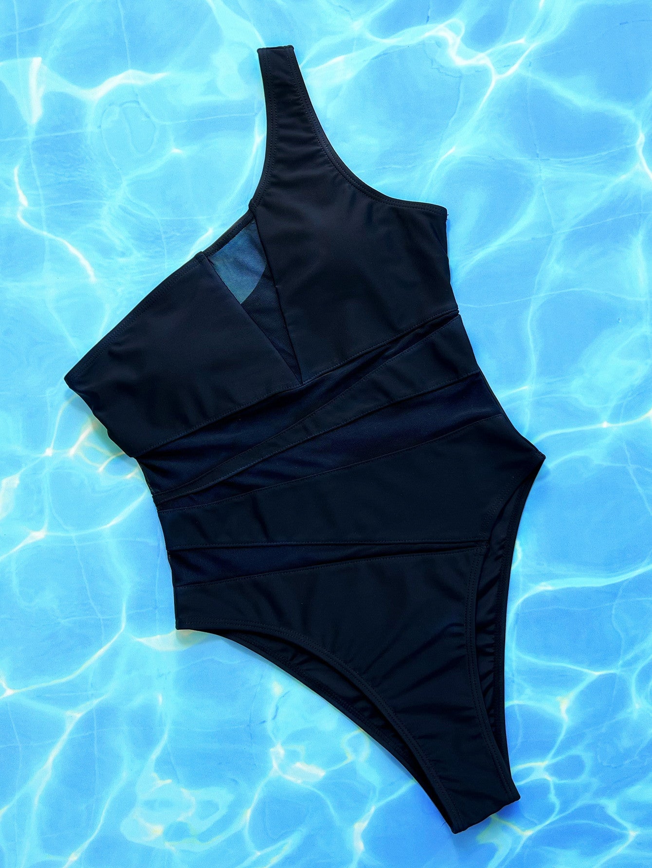 Black asymmetrical one-piece swimsuit with mesh panels and a high-cut leg.