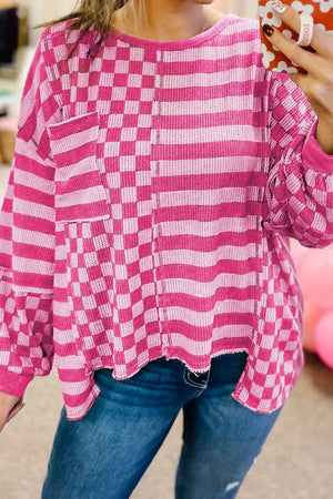 Hot Pink knit top with asymmetrical checkered and striped patchwork, crew neck, long sleeves, and pocket detail.