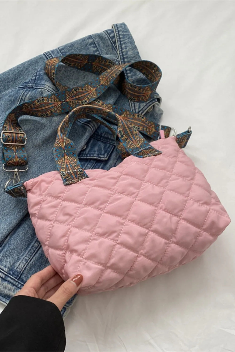 Blush pink quilted satchel with a patterned strap and denim jacket styling.