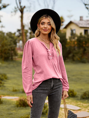 Pink ruffled henley blouse with button detail and long sleeves.