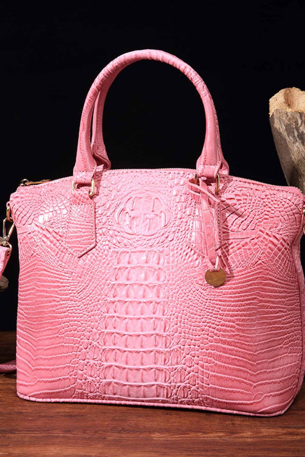 Pink crocodile embossed satchel bag with top handles and shoulder strap.