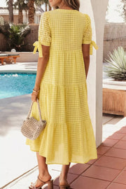 Yellow gingham midi dress with tiered skirt and tie-sleeve details.