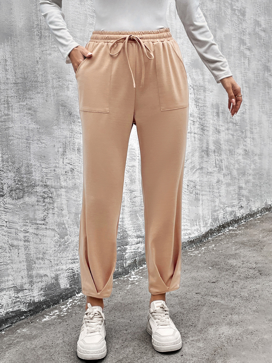 Beige tapered hem utility joggers with drawstring waist and patch pockets.