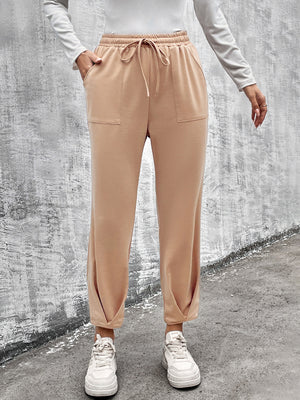Beige tapered hem utility joggers with drawstring waist and patch pockets.