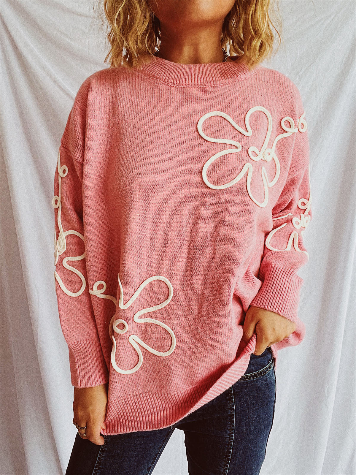 Watermelon pink knit sweater with outline floral pattern and crew neck.