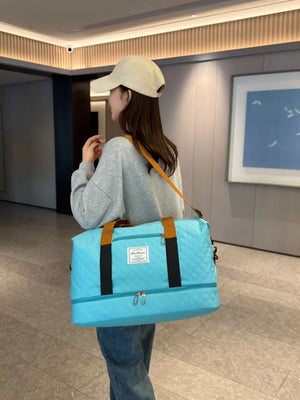 Luxurious quilted travel duffel bag in Lake Blue with brown handles and orange strap.