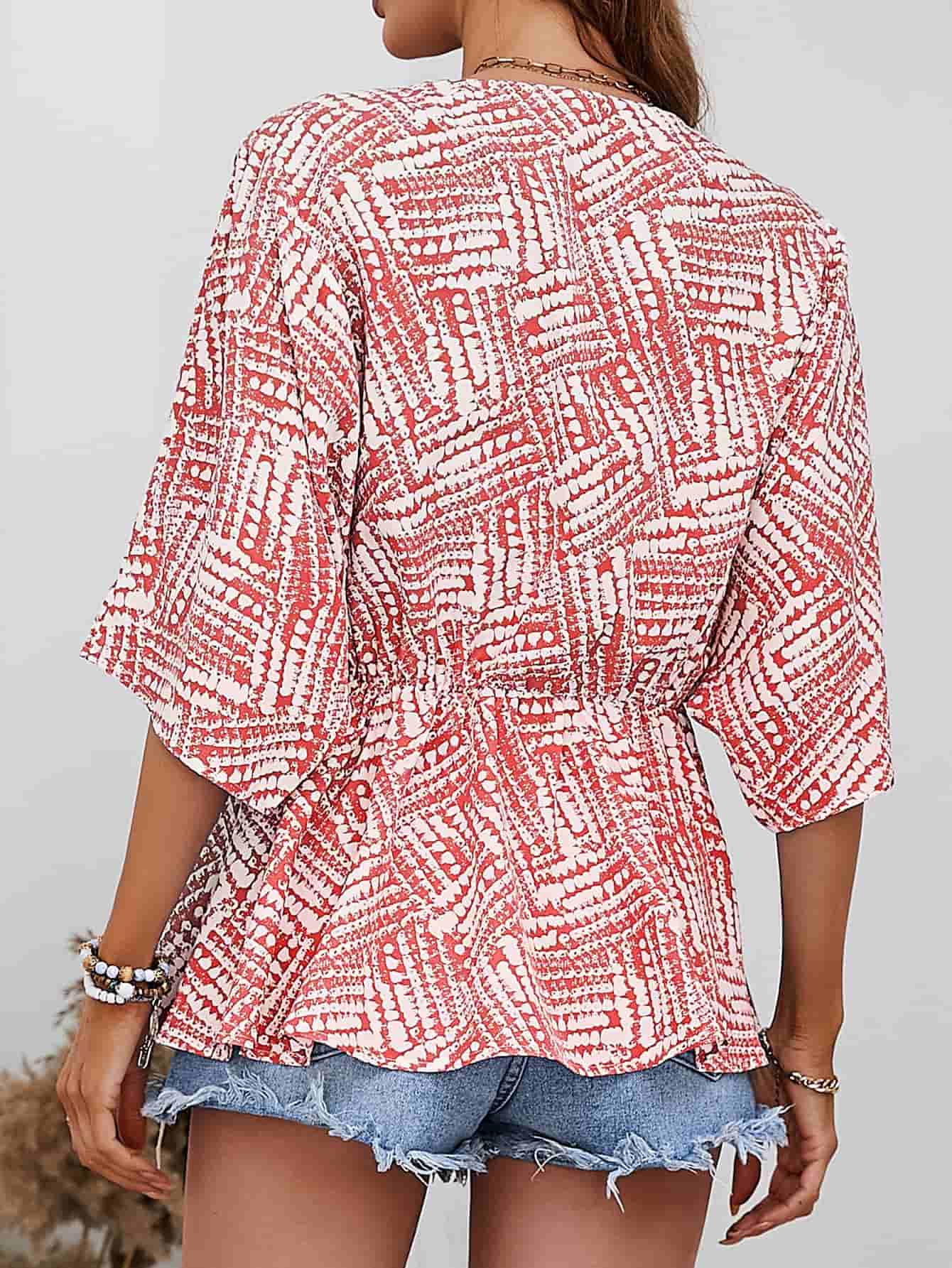 Abstract print cinched waist blouse in scarlet with short sleeves and a V-neck.