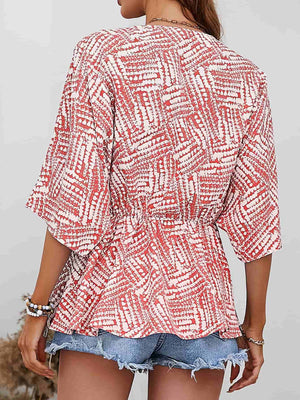 Abstract print cinched waist blouse in scarlet with short sleeves and a V-neck.