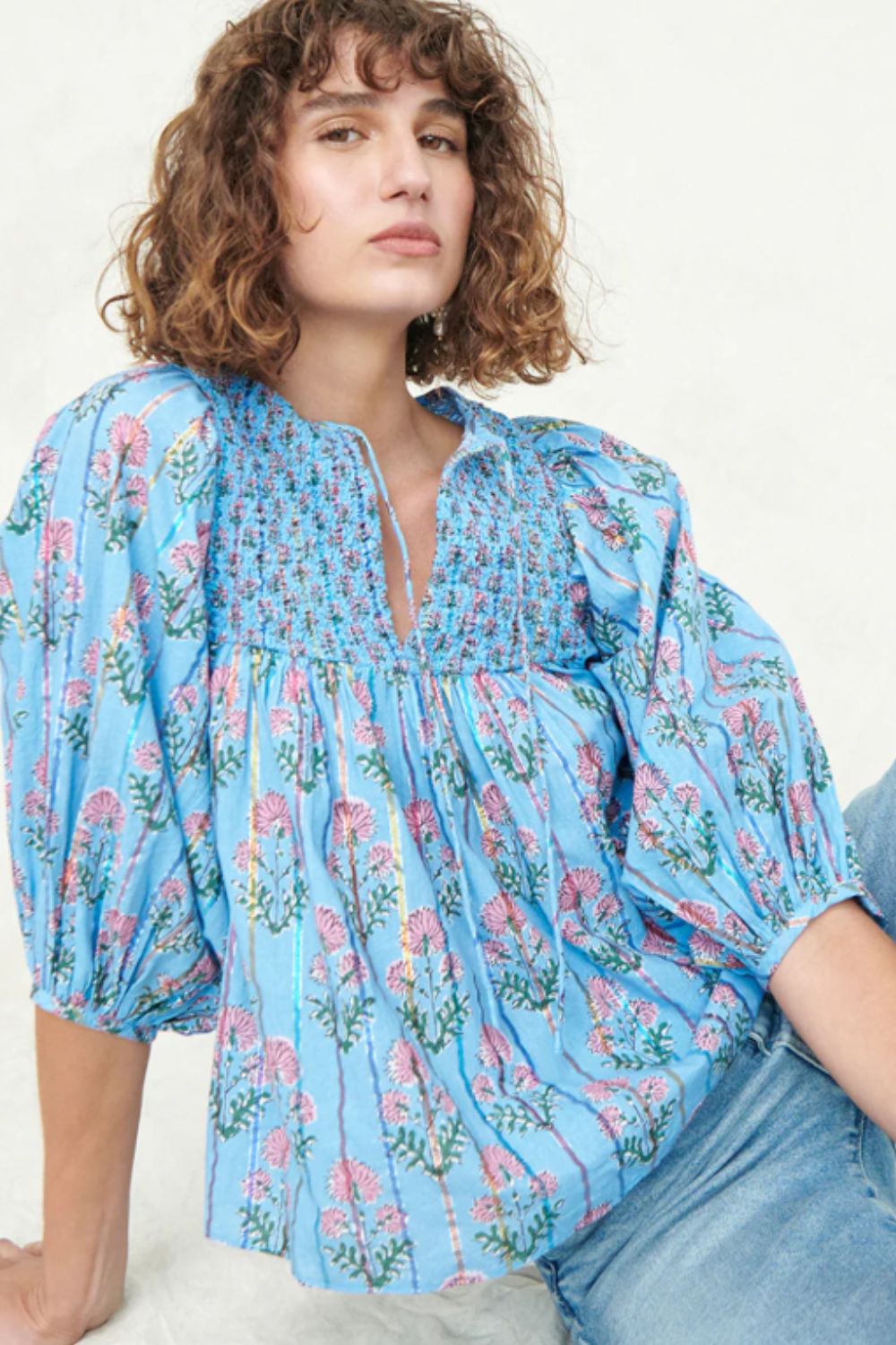 Sky blue floral print smocked yoke blouse with puff sleeves and tie neck.