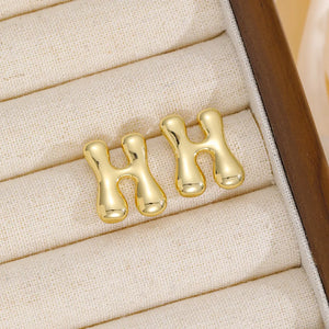 Gold sculptural stud earrings shaped like the letter H