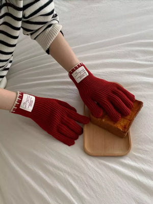 Red ribbed knit gloves with scalloped cuff and white trim detail.