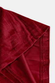 Plush velvet wide-leg trousers in burgundy showing seam detail and fabric texture.