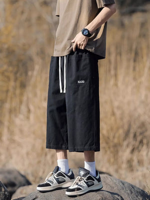 Black relaxed fit cropped sweatpants with drawstring and embroidered logo detail.