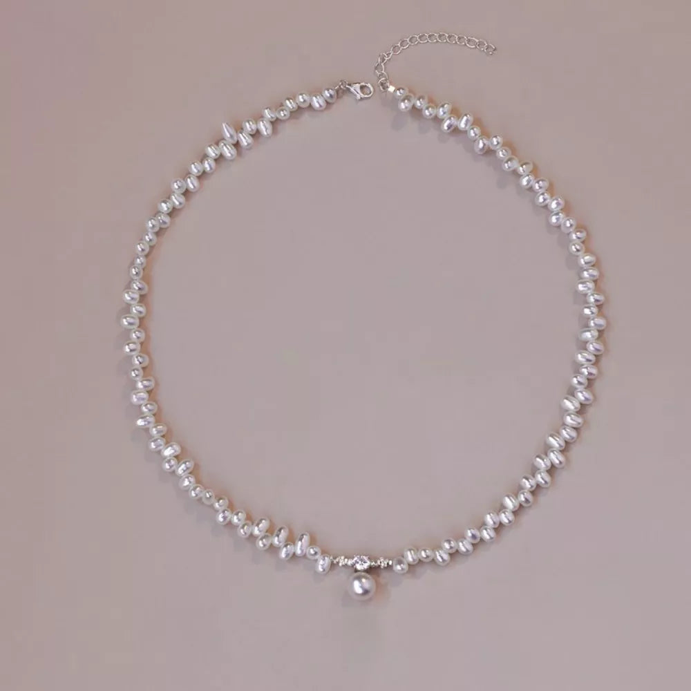 Lustrous irregular pearl pendant necklace with a single pearl drop and crystal accents.