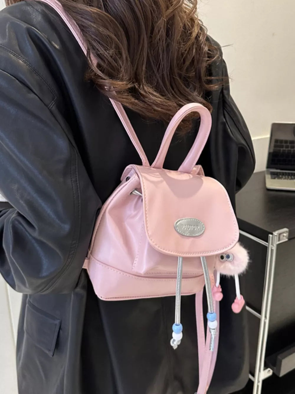 Pink leather mini drawstring backpack with beaded accents and fuzzy charm