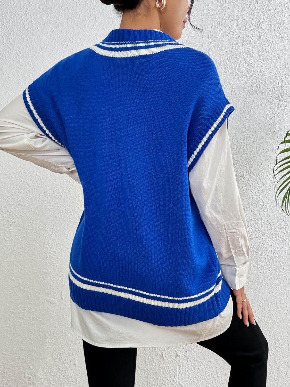 Blue acrylic knit vest with white varsity stripes and pearl trim detail, layered over a white shirt.